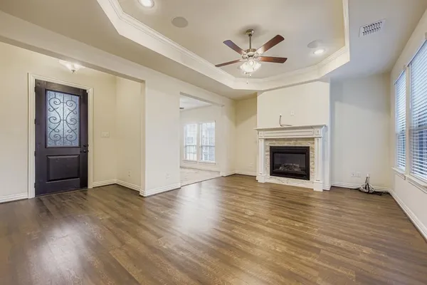 an empty room with wooden floor chandelier fan and windows