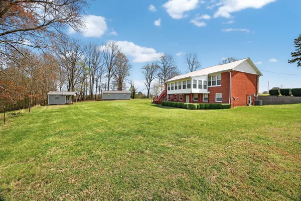 a view of a house with a big yard and large trees