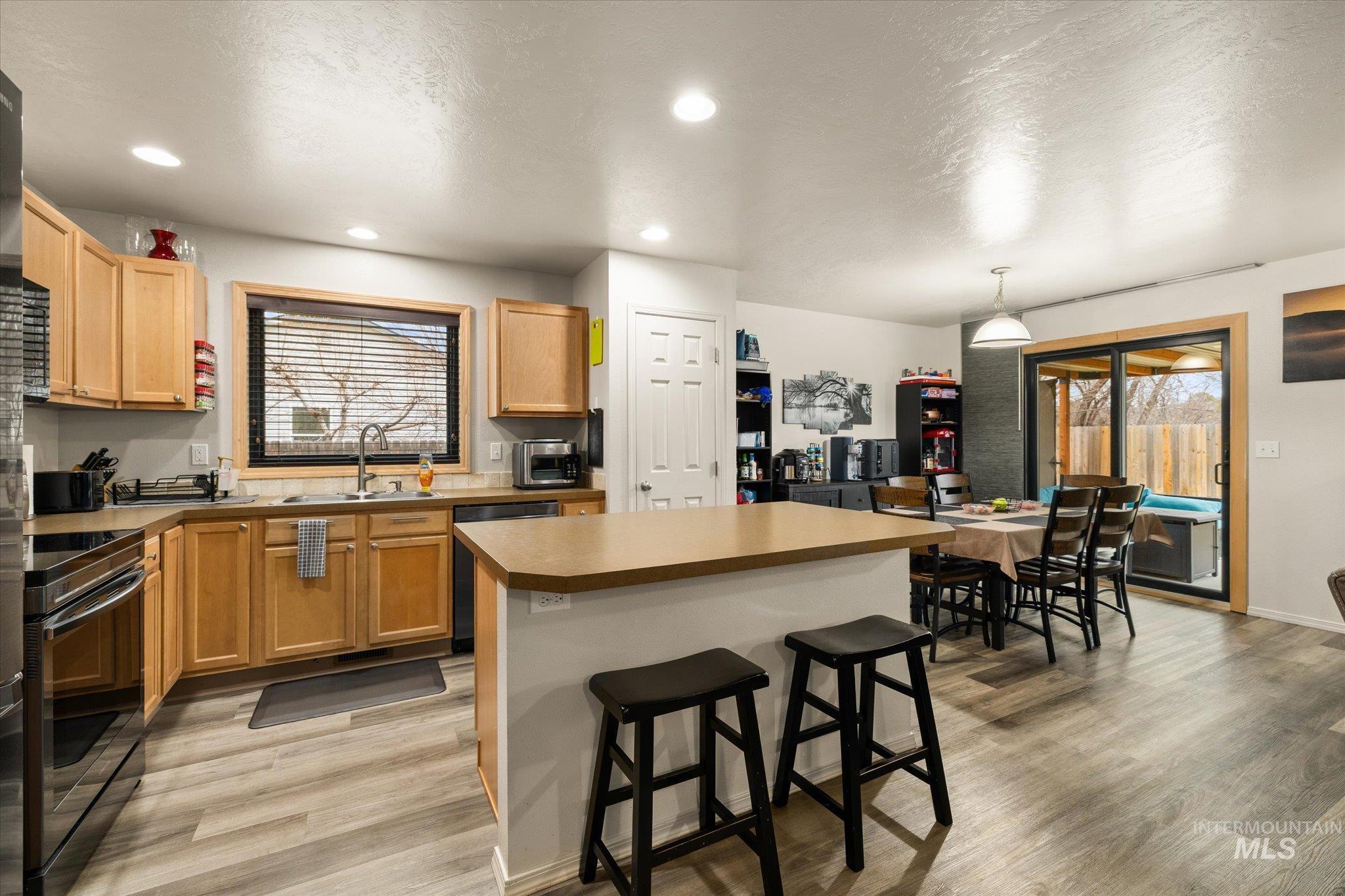 7166 Yellow Fern Road Nampa, ID 83687 - Photo 14 of 35 Kitchen featuring a breakfast bar area, a kitchen island, black / electric stove, light wood-type flooring, and dishwasher