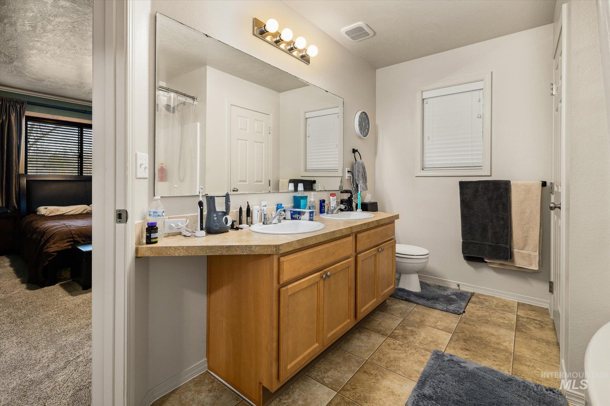 7166 Yellow Fern Road Nampa, ID 83687 - Photo 19 of 35 Full bathroom featuring double vanity, a shower with shower curtain, and light tile patterned floors