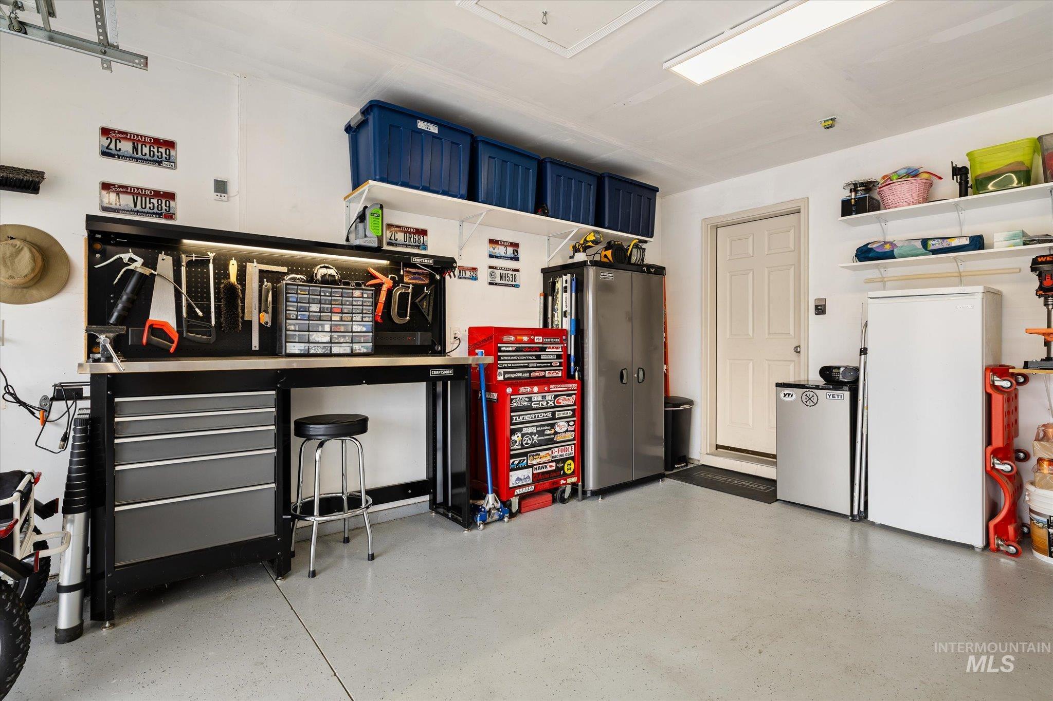 7166 Yellow Fern Road Nampa, ID 83687 - Photo 29 of 35 Garage featuring freestanding refrigerator, refrigerator, and a workshop area
