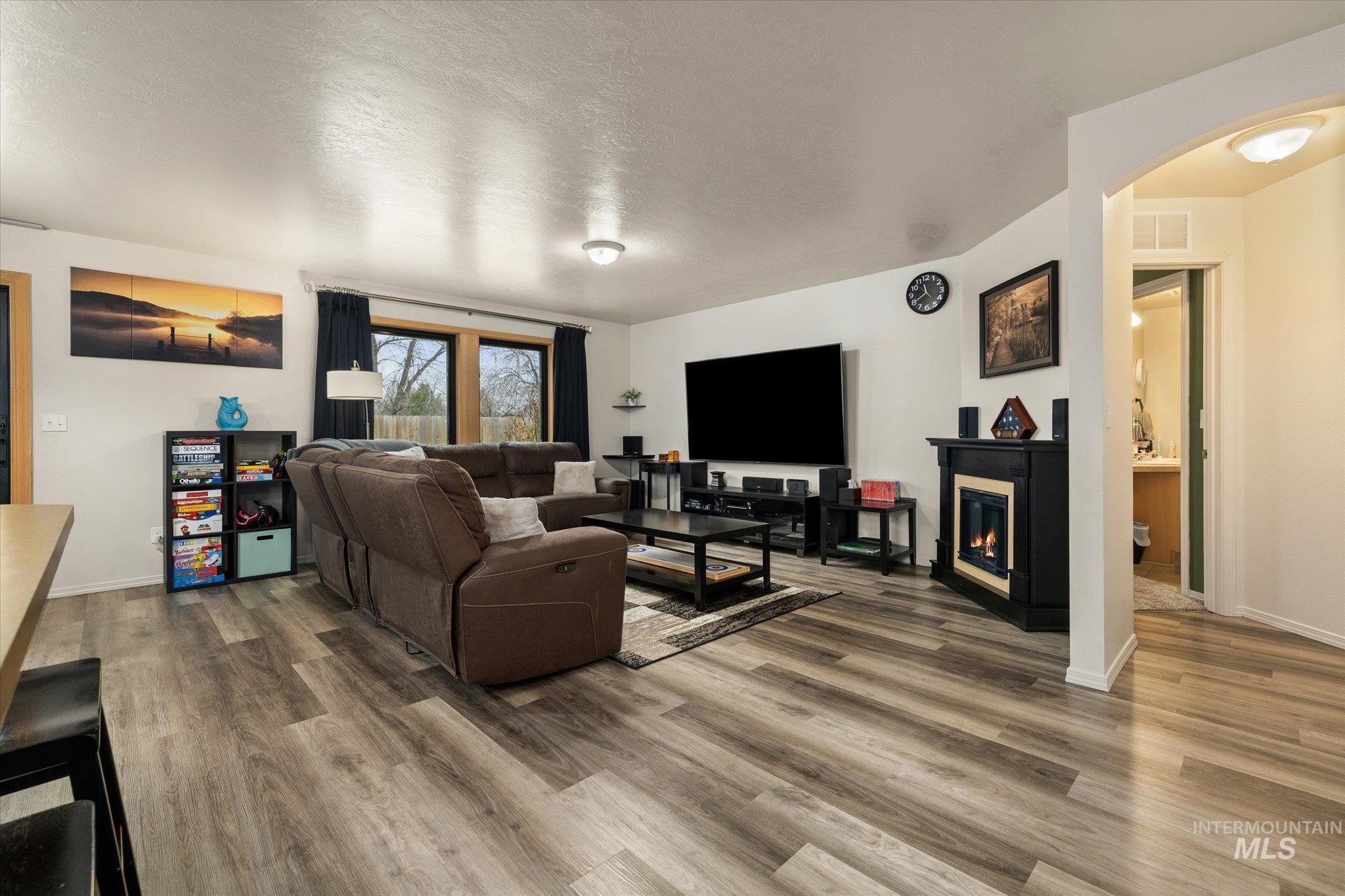 7166 Yellow Fern Road Nampa, ID 83687 - Photo 5 of 35 Living room featuring wood finished floors, a textured ceiling, and a glass covered fireplace