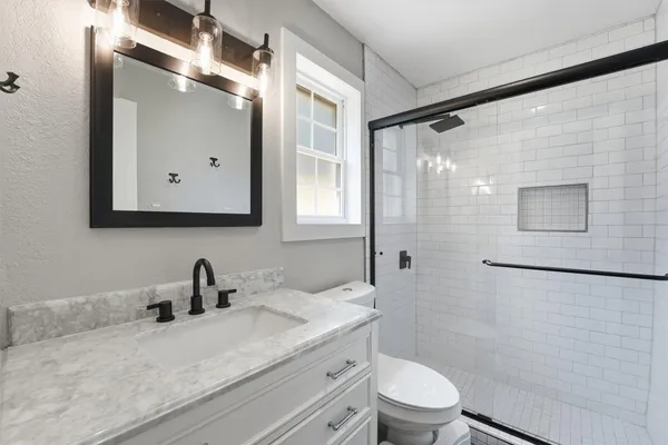 a bathroom with a double vanity sink toilet mirror and shower