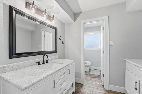 a bathroom with a granite countertop sink toilet and mirror