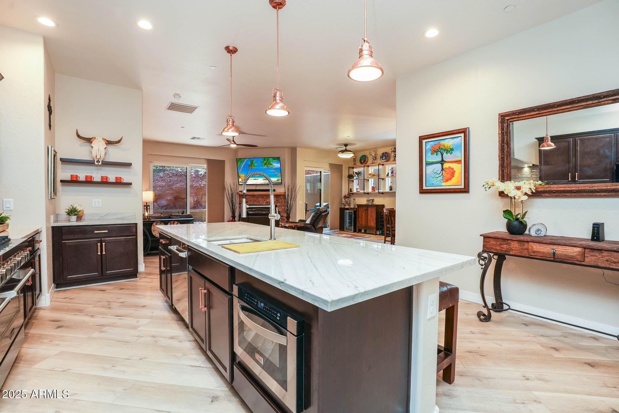 3835 Portofino Way Sedona, AZ 86336 - Photo 7 of 48 a large kitchen with stainless steel appliances a stove a sink a dining table and chairs with wooden floor