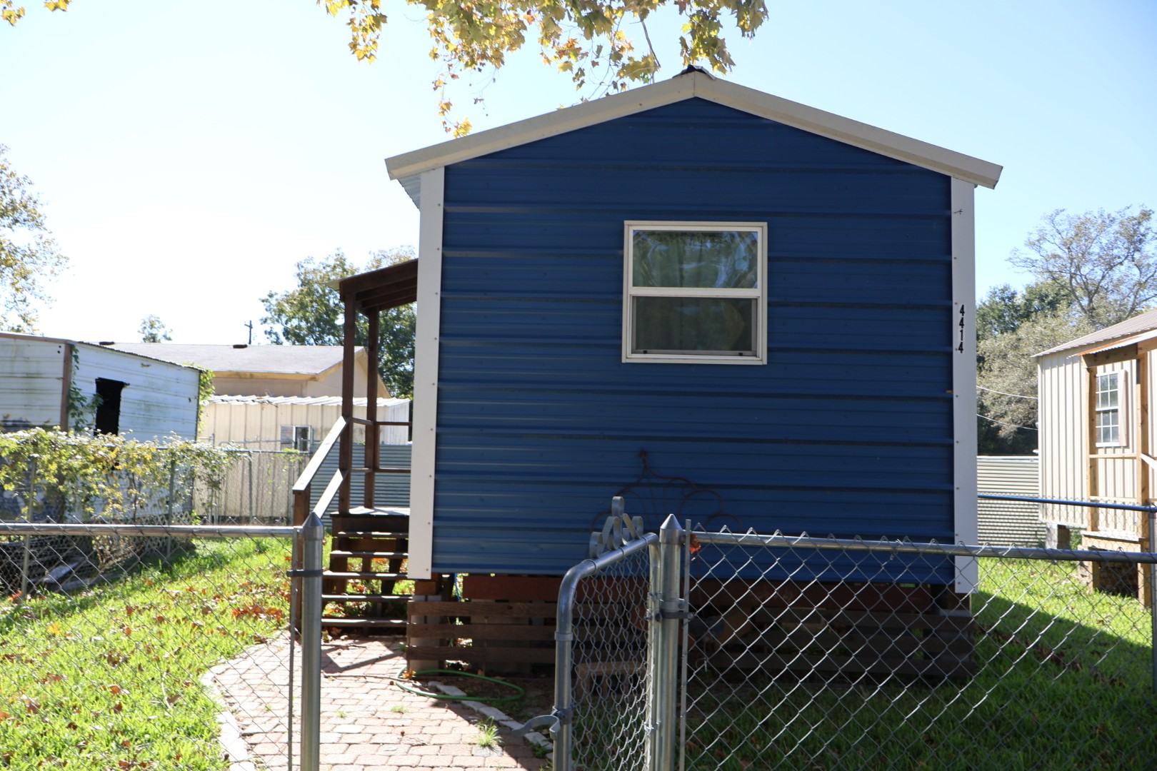 a view of brick house with a small yard and wooden fence