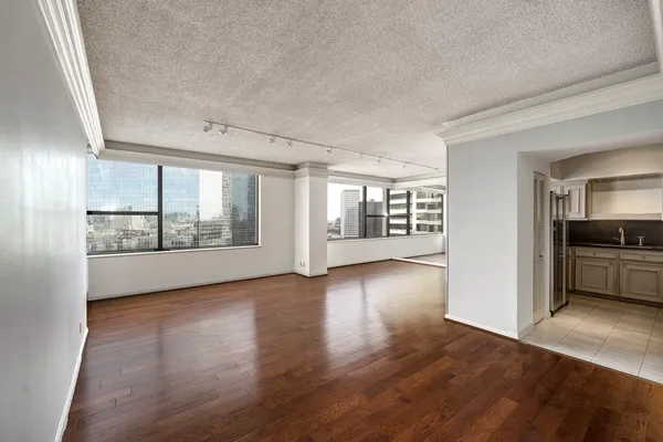 a view of an empty room with a window and wooden floor