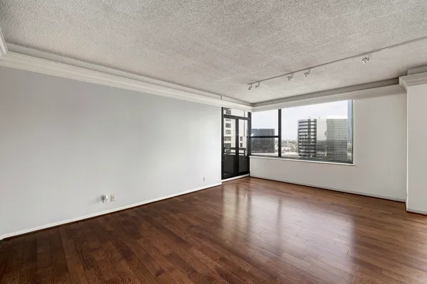a view of an empty room with a window and wooden floor