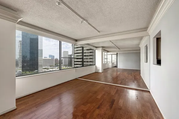 a view of an empty room with wooden floor and a window