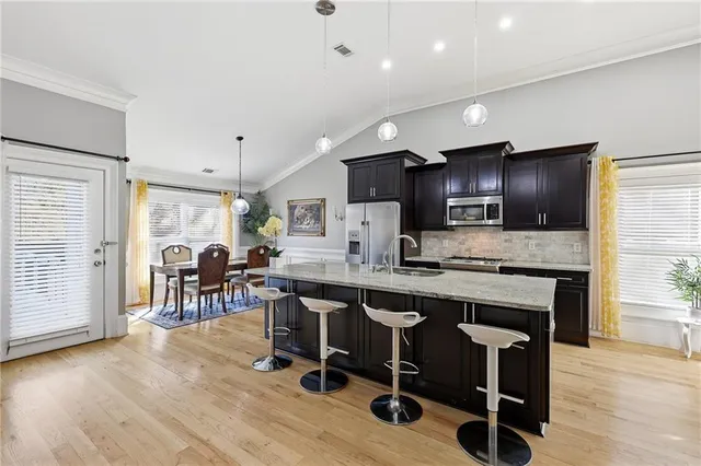 a kitchen with stainless steel appliances granite countertop a table chairs microwave and sink