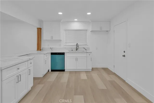 a kitchen with white cabinets a sink dishwasher and a stove with wooden floor