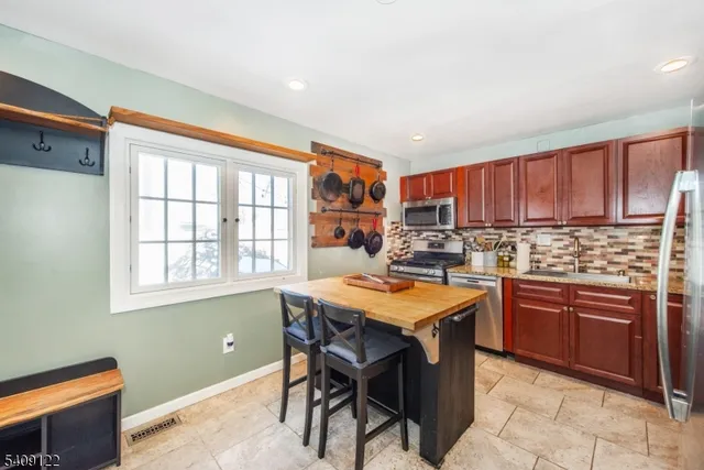 a kitchen with stainless steel appliances granite countertop table chairs sink and cabinets