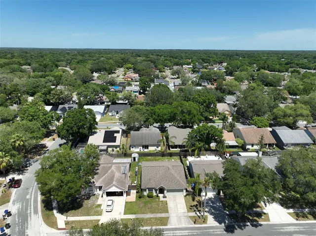 an aerial view of residential houses with outdoor space and trees