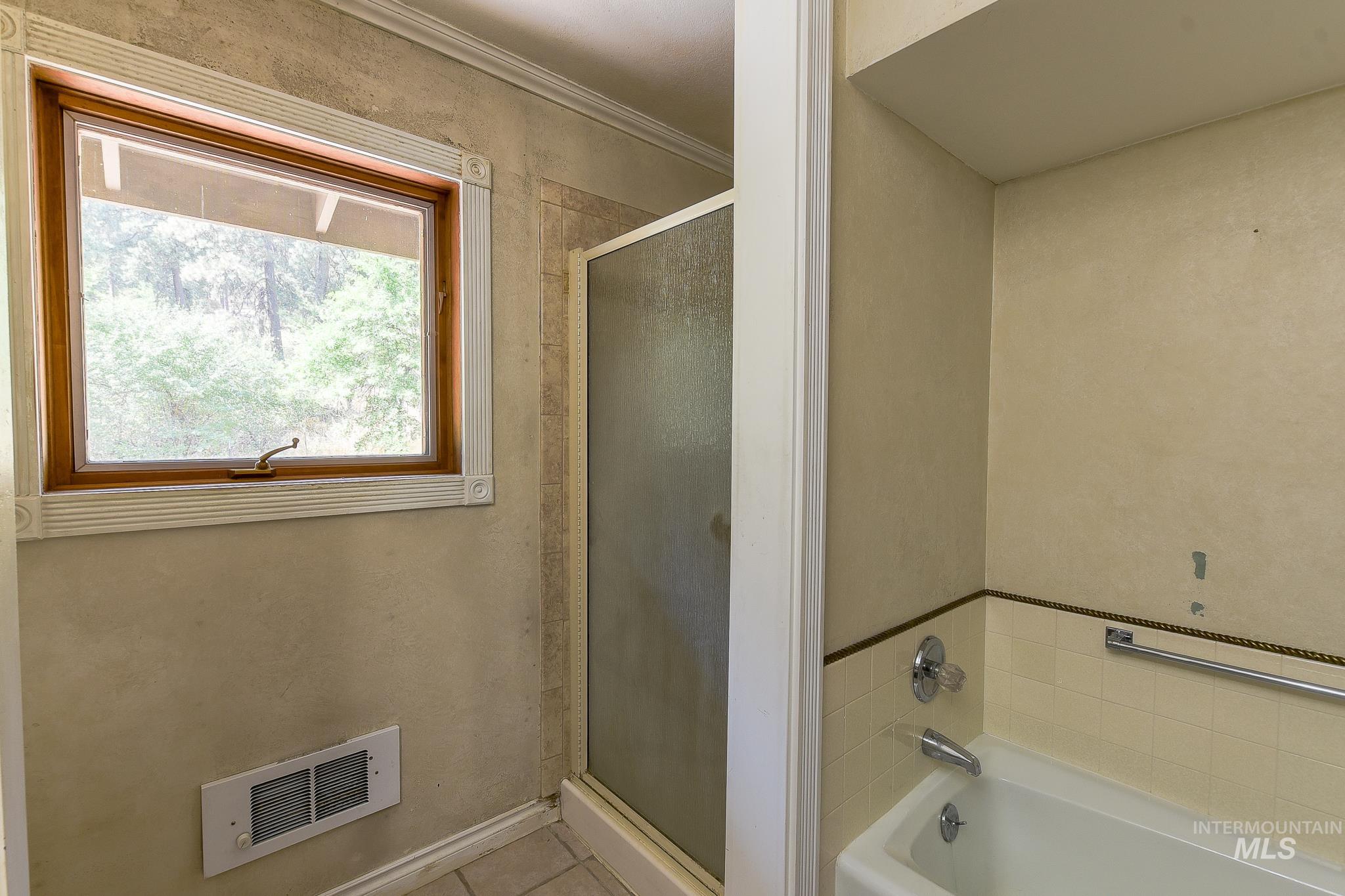 1045 Joyce Road Moscow, ID 83843 - Photo 28 of 50 Tile flooring, wood-framed window, shower enclosure, built-in bathtub, and wall-mounted heating element