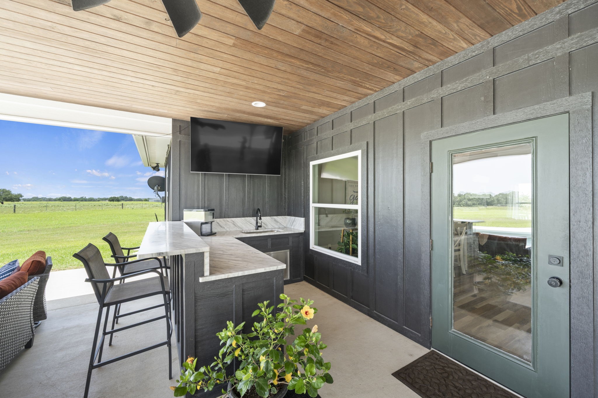 1655 Old Cuero Road Yoakum, TX 77995 - Photo 15 of 24 This covered outdoor living area is designed for year-round entertaining and relaxation. The custom outdoor kitchen features a spacious wraparound bar with granite countertops, bar seating, a built-in sink, beverage refrigerator, and mounted TV—perfect for hosting family and friends.