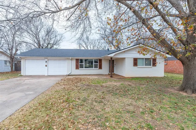 a view of a house with a yard and large tree