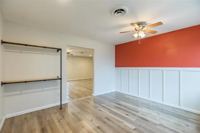 an empty room with wooden floor closet and windows