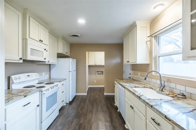 a kitchen with a sink stove cabinets and wooden floor