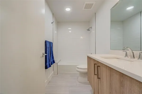 a bathroom with a granite countertop sink a toilet and a large mirror