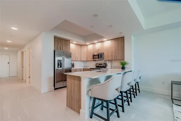a kitchen with kitchen island a counter top space a refrigerator and a sink
