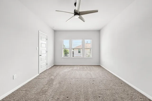 an empty room with a window and a ceiling fan