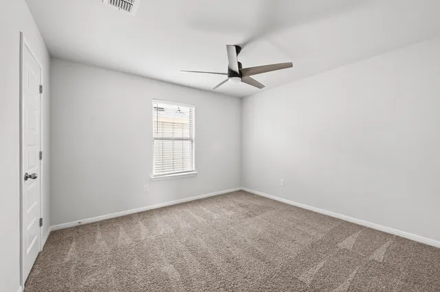 an empty room with a window and a fan