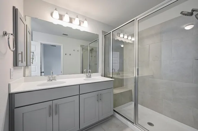 a bathroom with a double vanity sink mirror and shower