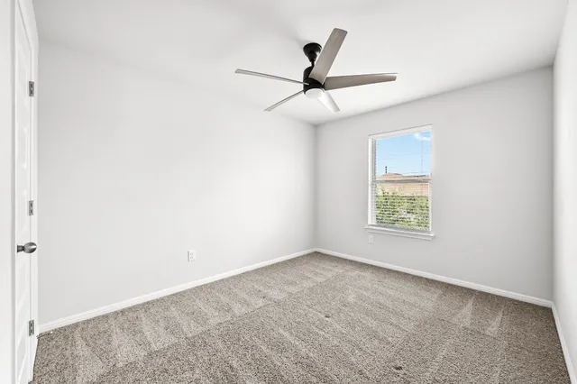 an empty room with a window and a ceiling fan