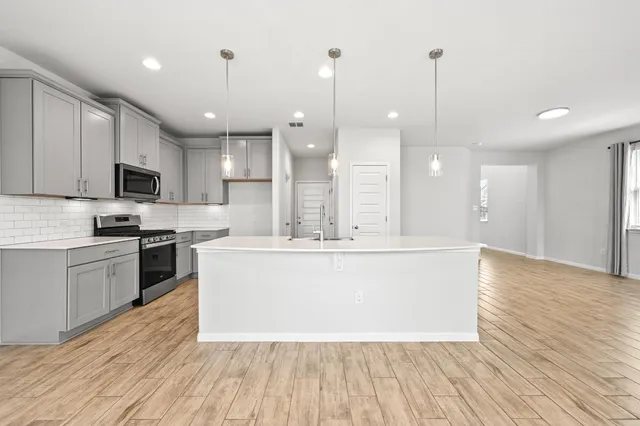 a large kitchen with stainless steel appliances a large counter top a sink a refrigerator and a window