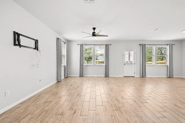 a view of an empty room with window and wooden floor