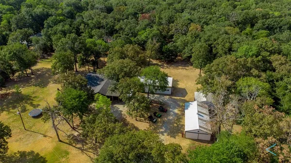 an aerial view of residential house with outdoor space and trees all around