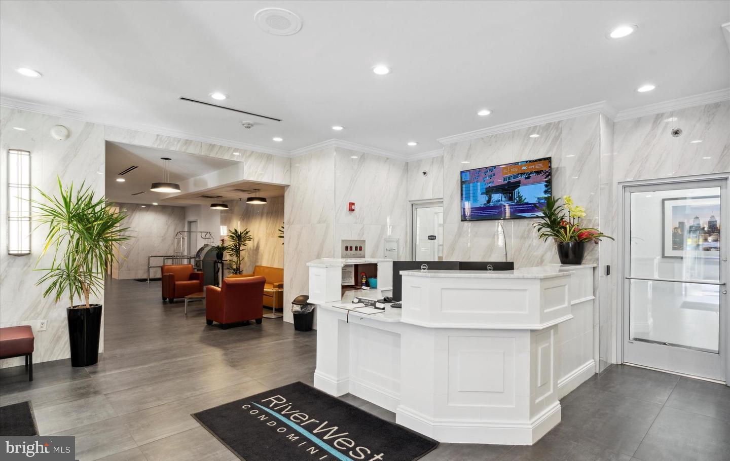 a large white kitchen with stainless steel appliances kitchen island granite countertop a couch and a view of living room