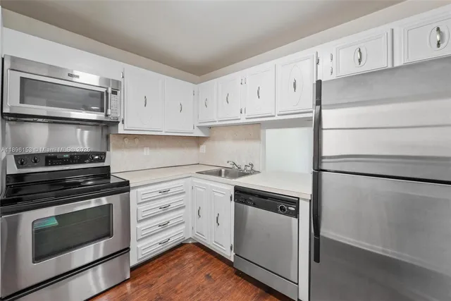 a kitchen with cabinets stainless steel appliances and wooden floor
