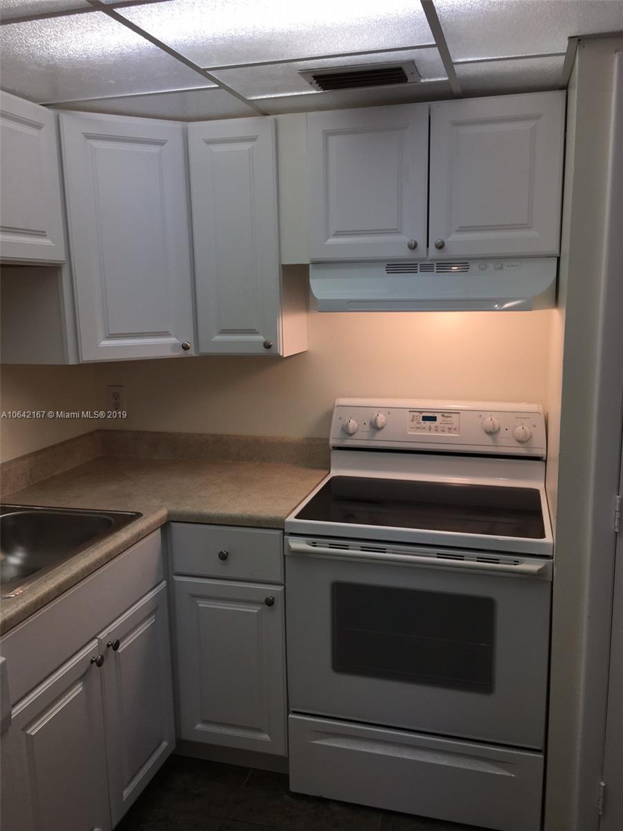 4164 Inverrary Drive, Unit 813 Lauderhill, FL 33319 - Photo 24 of 25 a kitchen with wooden cabinets and white appliances