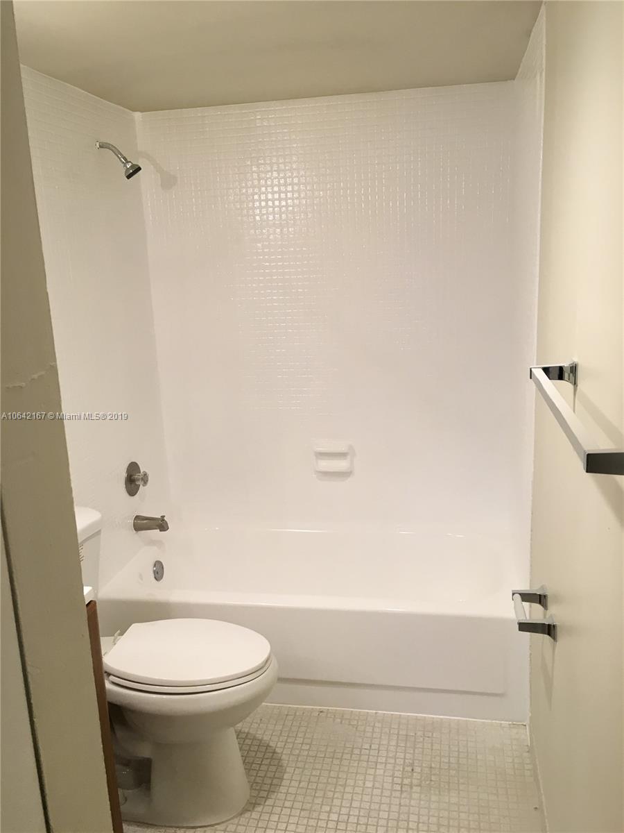 4164 Inverrary Drive, Unit 813 Lauderhill, FL 33319 - Photo 8 of 25 a bathroom with a white toilet and a shower curtain