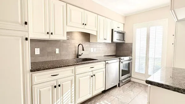 a kitchen with granite countertop white cabinets and white appliances
