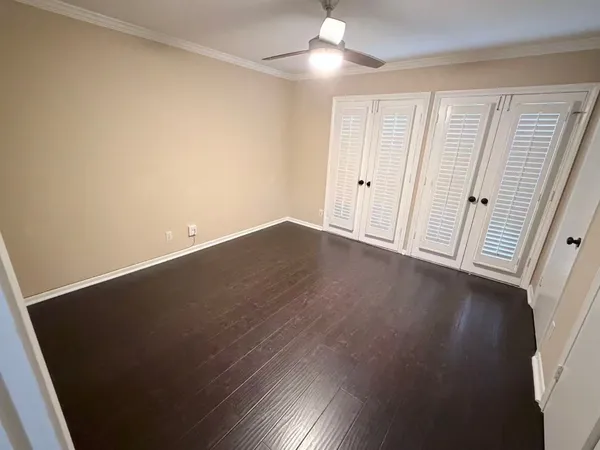 an empty room with wooden floor and fan
