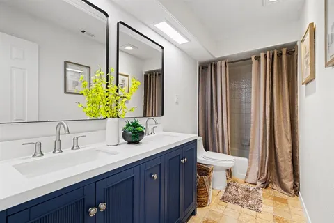 a bathroom with a double vanity sink toilet and a mirror