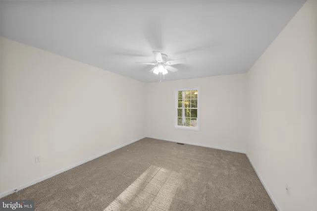 an empty room with a window and a ceiling fan