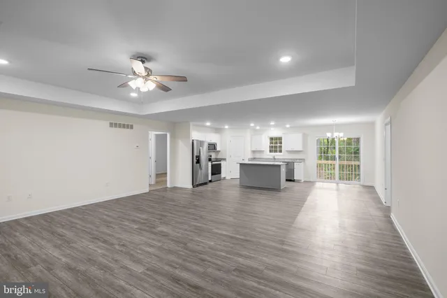 a view of an empty room with a kitchen and a window