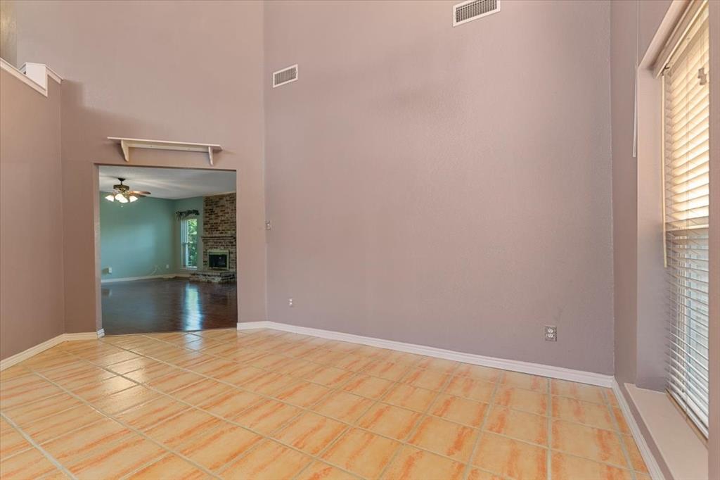 6752 MacIntosh Drive Plano, TX 75023 - Photo 12 of 40 Spare room featuring a towering ceiling, ceiling fan, plenty of natural light, a fireplace, and light tile patterned floors