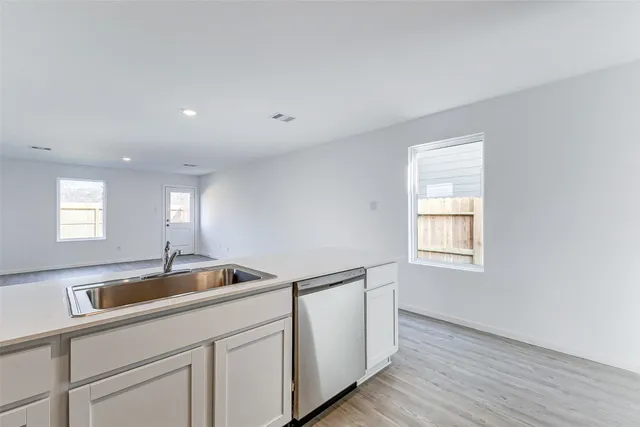 a kitchen with stainless steel appliances granite countertop a sink and white cabinets with wooden floor