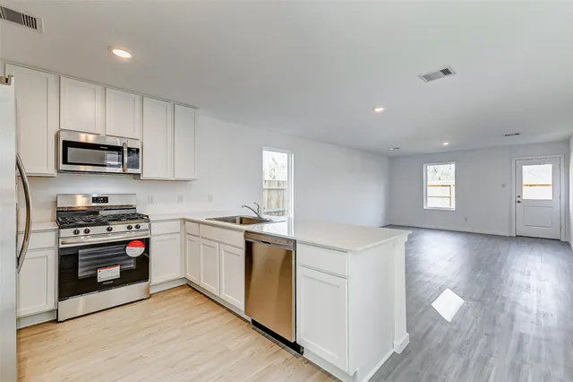 a kitchen with stainless steel appliances granite countertop a stove top oven a sink dishwasher and a refrigerator