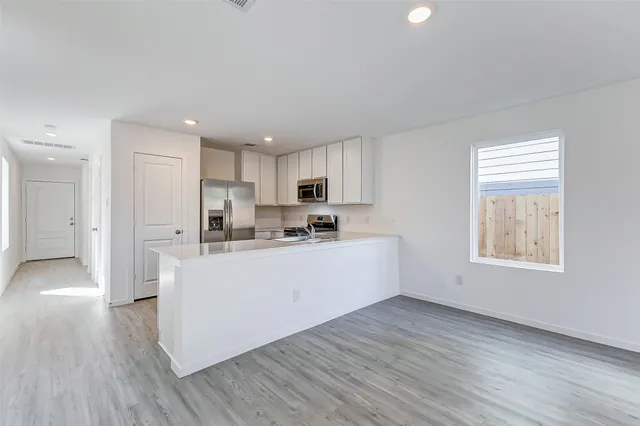 a kitchen with wooden floors white cabinets and refrigerator