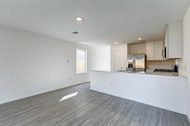 a large white kitchen with wooden floors and white walls
