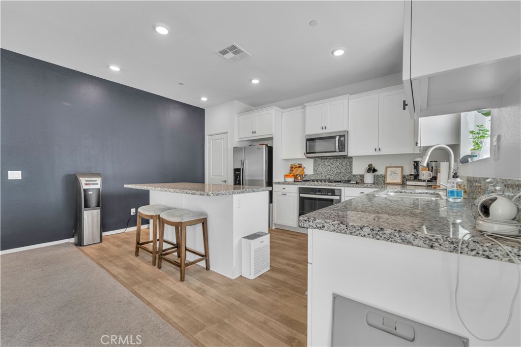 4422 Jade Court Lancaster, CA 93536 - Photo 26 of 44 a kitchen with a sink a stove a refrigerator and cabinets