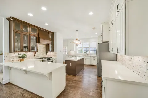 a large white kitchen with a large window and stainless steel appliances