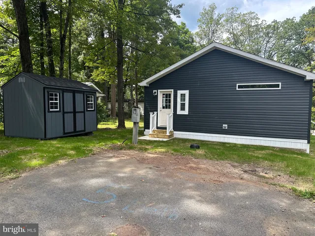 a backyard of a house with wooden fence and large trees
