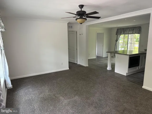 a view of a big room with windows and chandelier fan