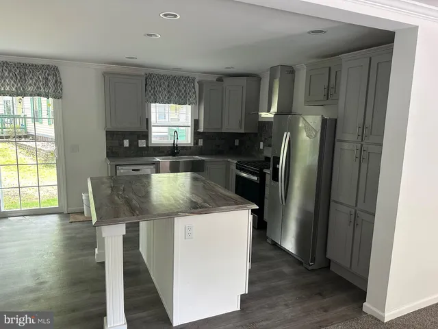 a kitchen with stainless steel appliances granite countertop a refrigerator a stove a sink and dishwasher with wooden floor